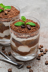 two portions Classic tiramisu dessert in a glass on concrete background