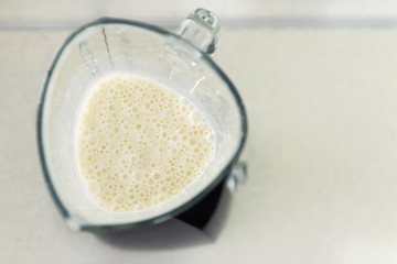 A young man prepares a smoothie of milk and fresh fruit for breakfast. He leads a healthy lifestyle.