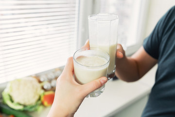 A young man prepared himself and girl for breakfast a smoothie from vegetable milk and fresh fruit....