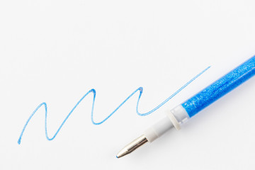 Blue gel pen with sparkles on a background of white paper. The concept of stationery for school, business and creative.