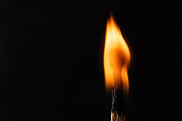 Burning match close-up on a dark background. Fire in the dark, light in a philosophical concept. Macro photo. Copy space.