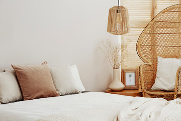 White and bright bedroom interior with wicker peacock chair and rattan lamp