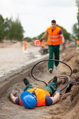 Accident during road construction, injured worker lying on the ground