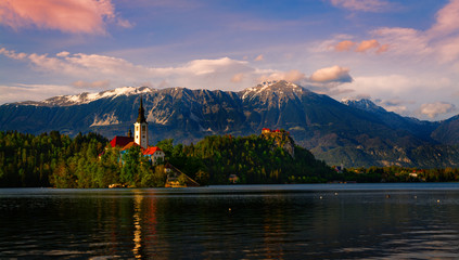 Lake Bled (Slovenia) at sunset, on the foreground the island with the church of the assumption of Mary, on the background the Bled Castle and the snowcapped Julian alps