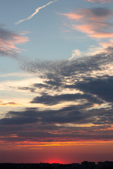 Fototapeta premium the pink sun sets over the city skyline, illuminating the dramatic clouds