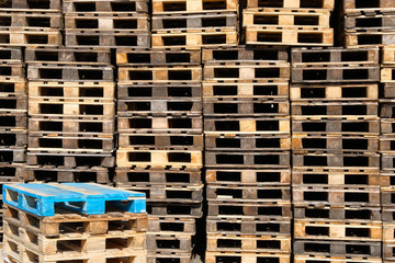 Pallets background. Stacks of old rough wooden pallets at warehouse in industrial yard. Cargo and shipping concept.