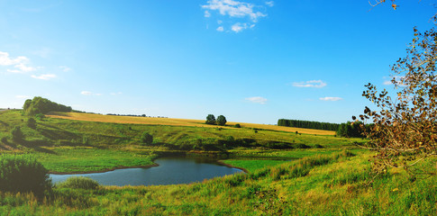 Naklejka premium Sunny summer landscape with river,green hills and fields