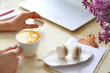 Top view shot of woman typing on white laptop computer, concrete textured table background. Feminine workspace with flowers bouquet. Close up, copy space.