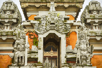 Balinese style hinduist stone temple decorated with statues of demons in Jakarta, Indonesia, Java island.