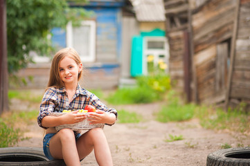 Girl in shirt and shorts with a basket of fruit. Girl farmer with apples and grapes. Concept of ecological food, person, fruit