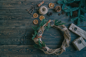 Christmas gift, rustic wreath with decorations, pine cones, fir branches on wooden brown background. Merry Christmas and Happy Holidays concept. Flat lay, top view, copy space. Toned image. Vintage.