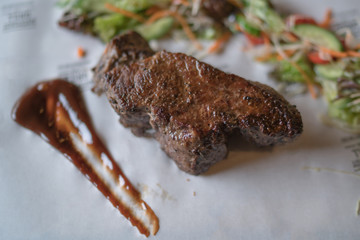 Sirloin steak on cutting board and paper. Eating and leisure concept. Roasted beef. Delicious hot beef steak. Grilled beef steaks with vegetables. Organic healthy food. Toned image. Selective focus.