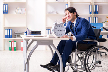 Young male employee in wheelchair working in the office 