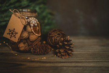 Christmas gift with homemade gingerbread cookies, nuts and chocolates. Glass jar, fir branches, Christmas spices and decor. Winter holidays, New Year or Christmas concept. Toned image. Soft focus.