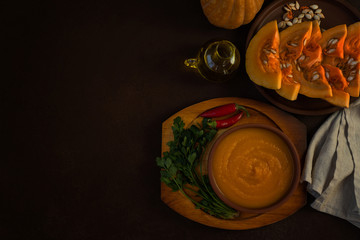 Bowl of pumpkin organic soup with cream and pumpkin seeds on gray background. Dietary vegetarian food. Concept of healthy eating food. Homemade autumn soup. Top view with copy space. Toned image.