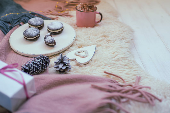 Christmas background with decorations and paper gift box on rustic wooden floor. Presents, decoration, fir cones, cup of coffee and cake. Preparation for the happy holidays. Toned image. Soft focus.