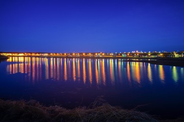 The reflexions in a river from the lights of a town in the north of Iceland, captured at night with long exposure