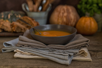 Vegetables cream soup and ingredients. Concept of healthy eating or vegetarian food. Dietary vegetarian pumpkin cream soup puree, on dark brown wooden table. Copy space. Toned image. Soft focus.