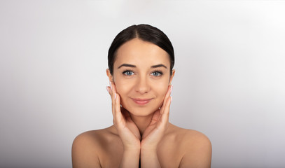 Obraz premium beautiful brunette girl with blue eyes, white background, beauty, touches her face with her hands