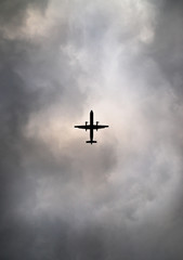 Commuter airplane silhouetted against cloudy sky 