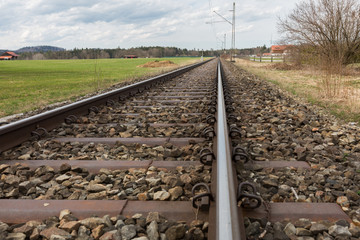 Railway tracks leading into the distance. On the left a glimpse of the scenery of the Bavarian...