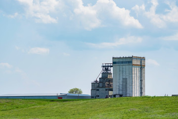 Fototapeta na wymiar White grain elevator in green steppe nature