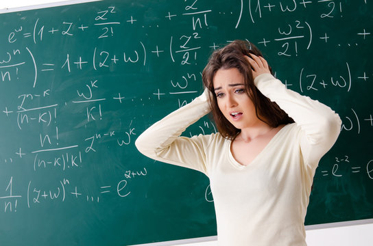 Young female math teacher in front of chalkboard  
