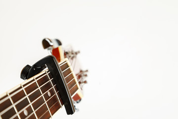Acoustic guitar neck with capo on a white background