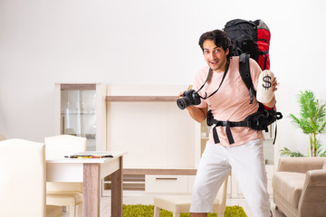 Young male tourist preparing for trip at home 
