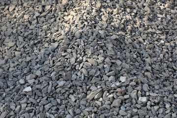 Gray textured surface of a heap of construction pebbles and gravel