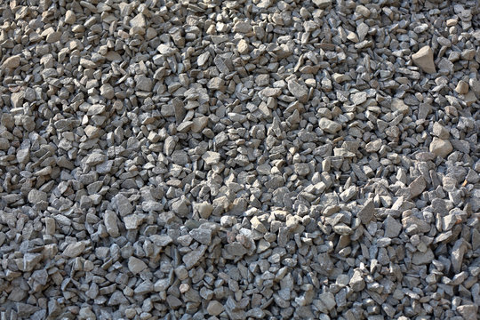 Gray textured surface of a heap of construction pebbles and gravel