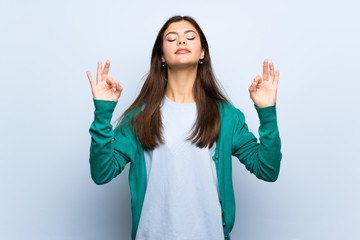 Teenager girl over blue wall in zen pose