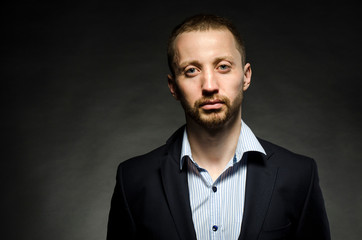 Fototapeta premium fine portrait of a white man with a beard in a business suit on a black background