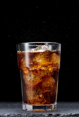 glass of cola with ice on black background - obrazy, fototapety, plakaty