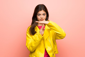 Teenager girl over pink wall making time out gesture