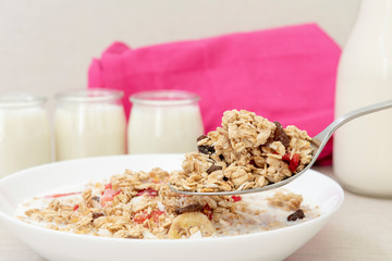 Spoon and bowl of cereals with milk and fruits