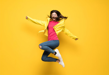 Fototapeta na wymiar Teenager girl jumping over isolated yellow wall