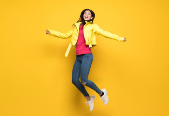 Teenager girl jumping over isolated yellow wall