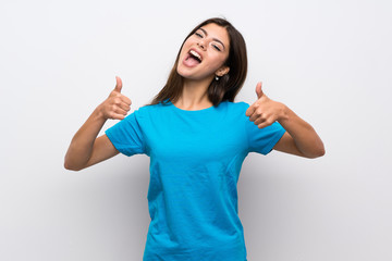 Teenager girl with blue shirt with thumbs up gesture and smiling