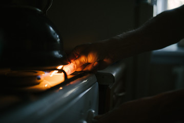 A man lights a match on a gas stove with a match