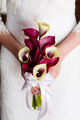 Unrecognizable bride holding a refined wedding bouquet of white and crimson callas