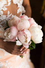 Fototapeta na wymiar A charming wedding bouquet of pink peonies, in the hands of an unrecognizable bride