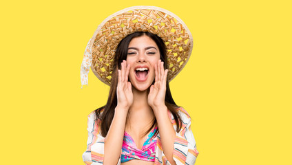Teenager girl on summer vacation shouting and announcing something over isolated yellow background