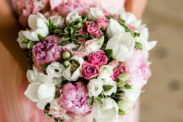 Unrecognizable bride holding a refined wedding bouquet of pink roses and peonies with white eusmoy and tulips