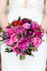 Exquisite bouquet of red and pink roses and peonies in the hands of the bride