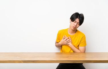 Asian man with yellow shirt having a pain in the heart