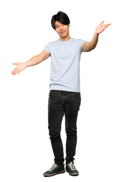 A full-length shot of a Asian man with blue shirt presenting and inviting to come with hand over isolated white background