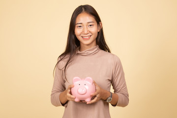 Young Asian woman with a pig coin bank.