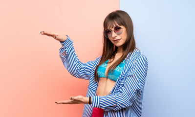 Young woman in bikini holding copyspace to insert an ad