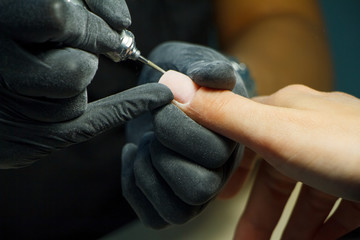 Manicure process close-up with nail polishing machine. Hardware manicure in modern beauty salon.